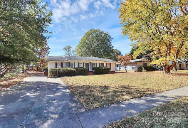 a front view of a house with a yard and large trees