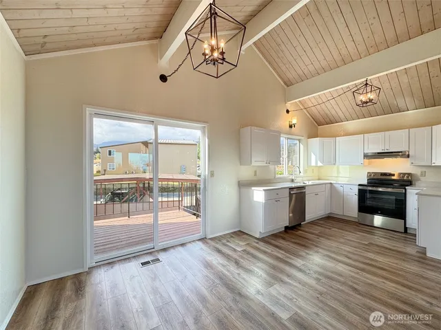 a kitchen with stainless steel appliances a refrigerator a sink dishwasher a stove and white cabinets with wooden floor