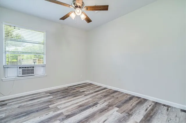 an empty room with a window and a fan