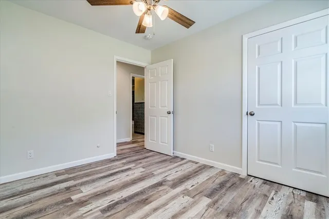 an empty room with wooden floor closet and chandelier fan