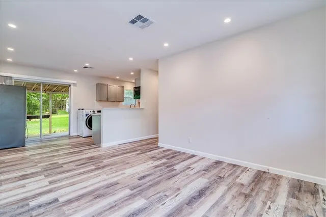 a view of an empty room with a window and wooden floor