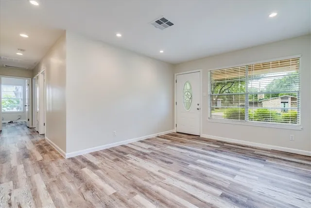 a view of an empty room with wooden floor and a window