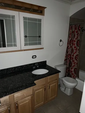 a bathroom with a granite countertop sink and a toilet
