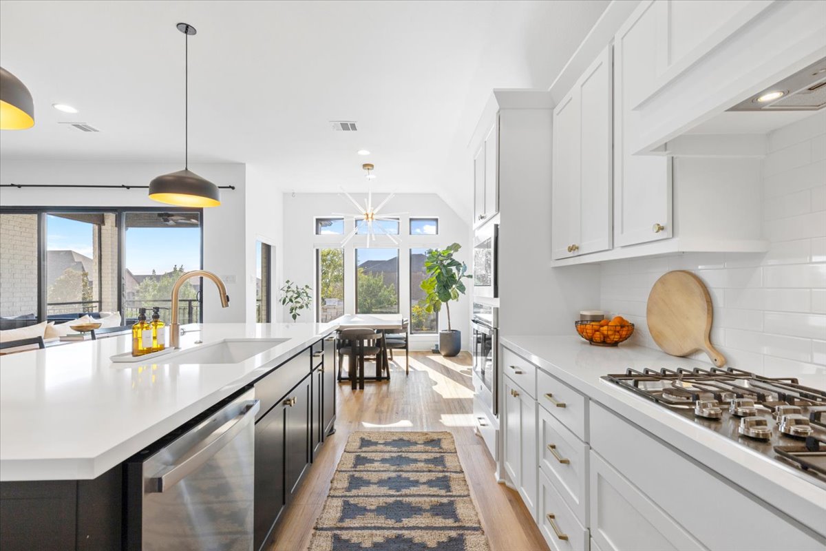 398 Trout River Road Kyle, TX 78640 - Photo 15 of 40 Dual tone kitchen with dual tone cabinetry, stainless steel appliances, pendant lighting, light wood finished floors, and an island with sink
