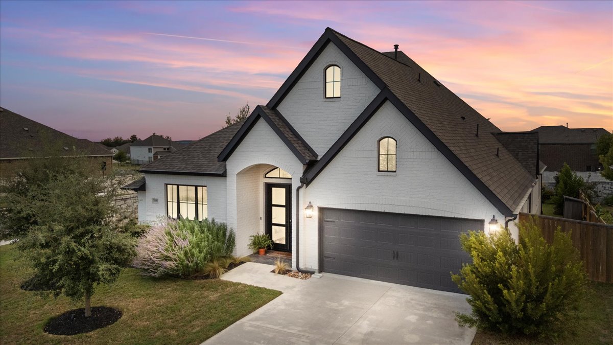 398 Trout River Road Kyle, TX 78640 - Photo 2 of 40 French country style house with a garage, concrete driveway, a shingled roof, and brick siding