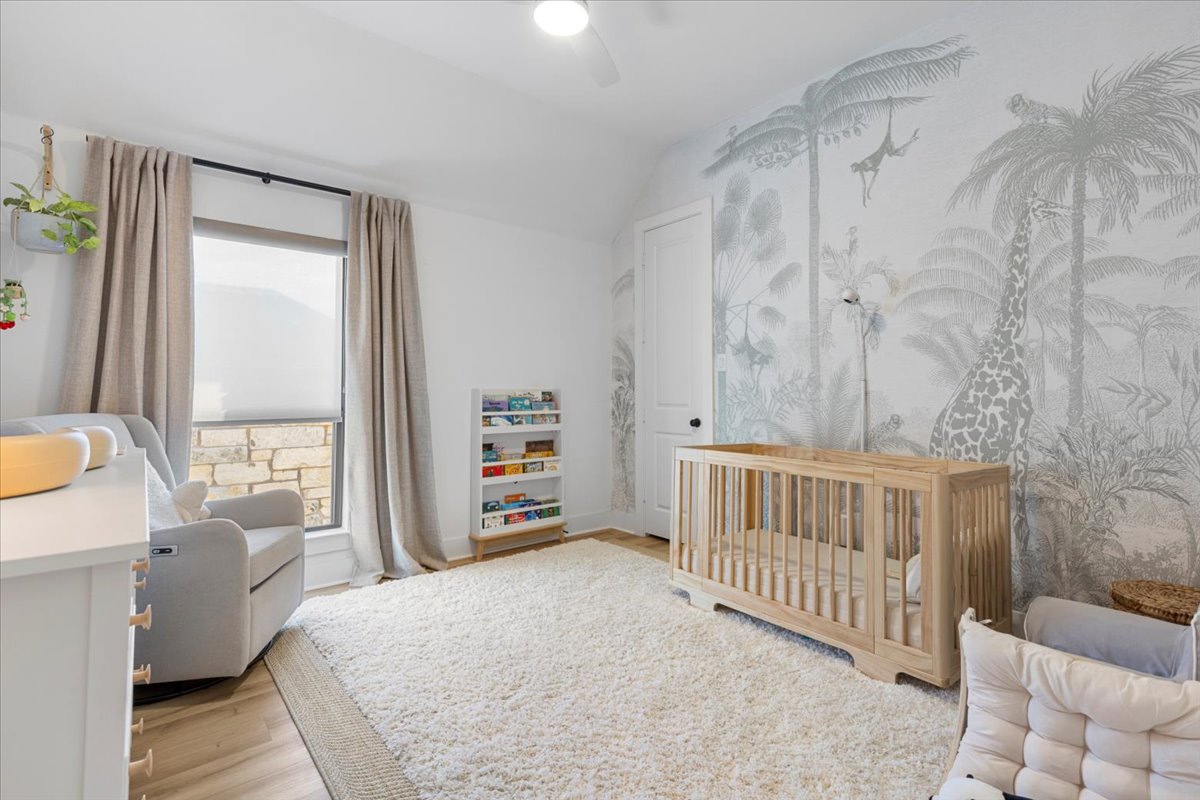 398 Trout River Road Kyle, TX 78640 - Photo 26 of 40 Bedroom with a crib, light wood-type flooring, lofted ceiling, and a ceiling fan