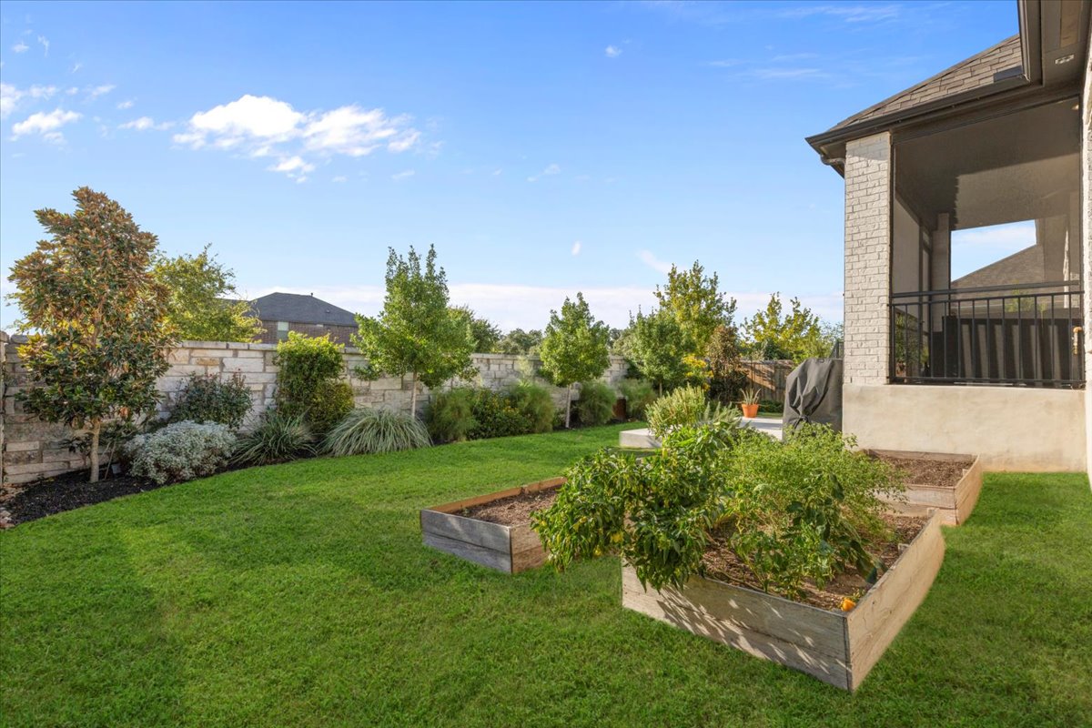 398 Trout River Road Kyle, TX 78640 - Photo 33 of 40 Fenced backyard with a vegetable garden and a sunroom