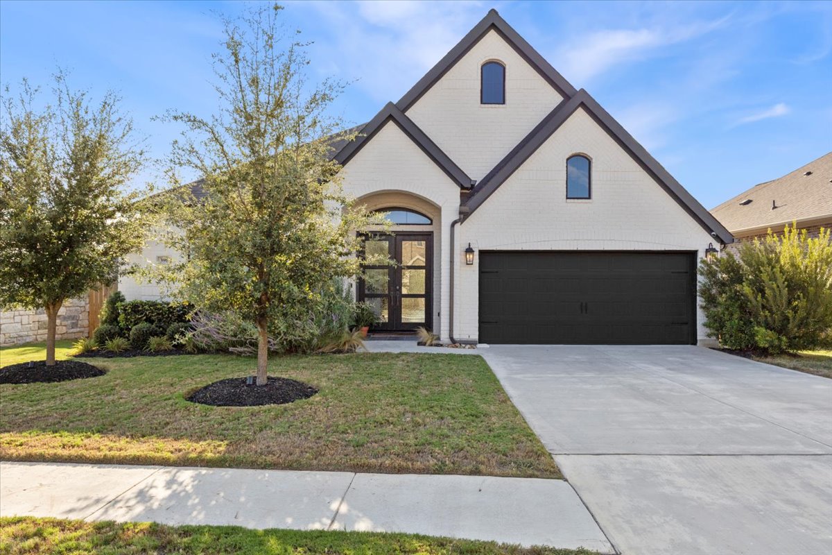 398 Trout River Road Kyle, TX 78640 - Photo 4 of 40 View of front of property with french doors, brick siding, a front yard, a garage, and concrete driveway