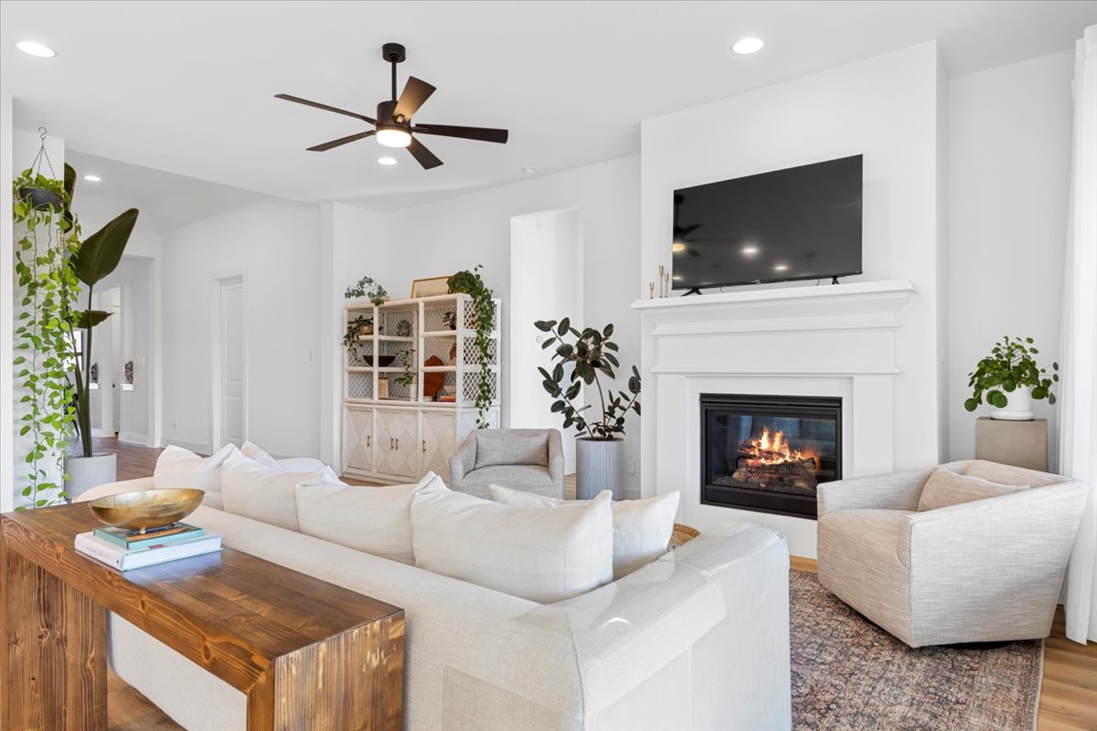 398 Trout River Road Kyle, TX 78640 - Photo 9 of 40 Living room with a glass covered fireplace, recessed lighting, a ceiling fan, and wood finished floors