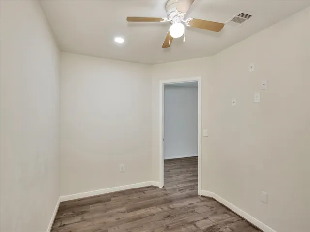 en empty room with wooden floor and ceiling fan