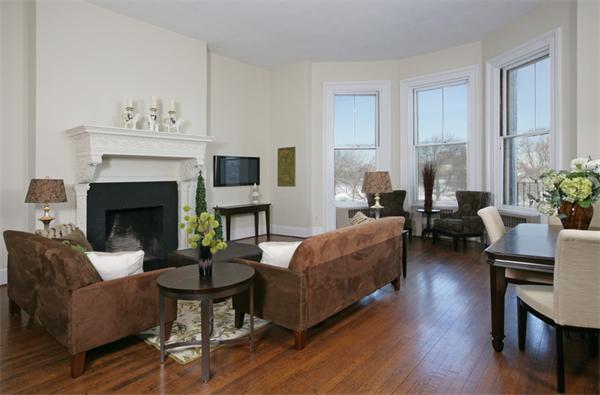 a living room with furniture a fireplace a potted plant and a window