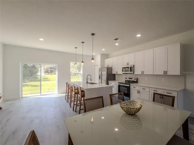 a kitchen with a dining table chairs and stainless steel appliances