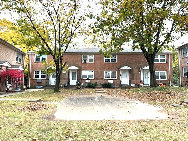 a front view of a house with a yard covered with snow and trees