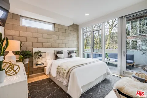 a bedroom with a bed and a large mirror next to a large window