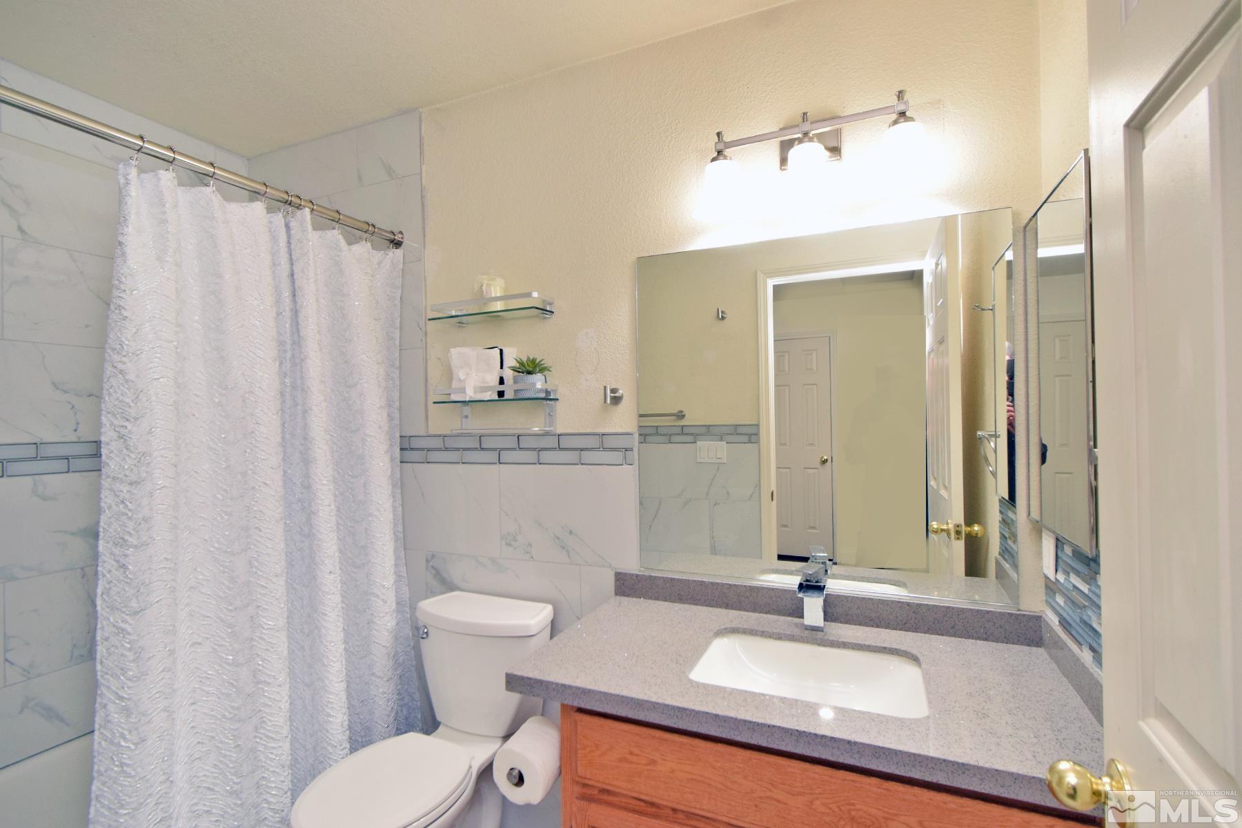 902 Vine Street Reno, NV 89503 - Photo 19 of 20 a bathroom with a sink a toilet a mirror and shower curtain
