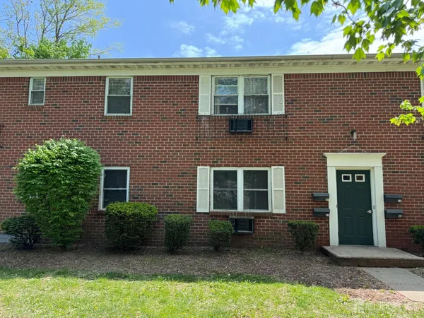 a view of a brick house with a yard and plants