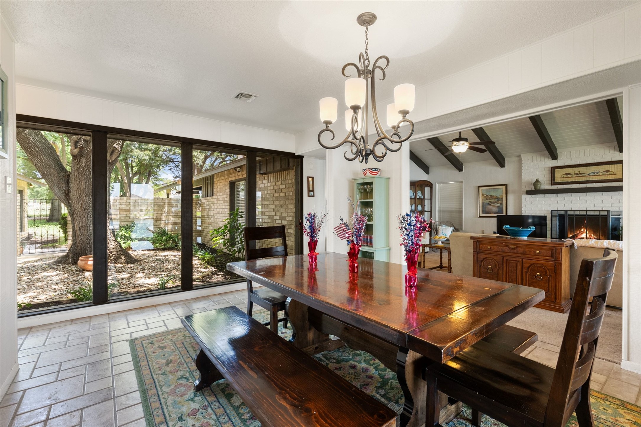 141 Perry Lane Kingsland, TX 78639 - Photo 19 of 40 A refined chandelier illuminates the dining area, featuring a grand wooden table and serene views of the outdoor space.