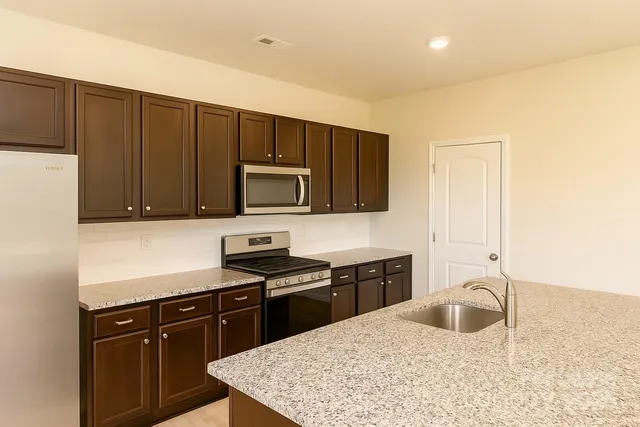 a kitchen with stainless steel appliances granite countertop a sink stove and microwave