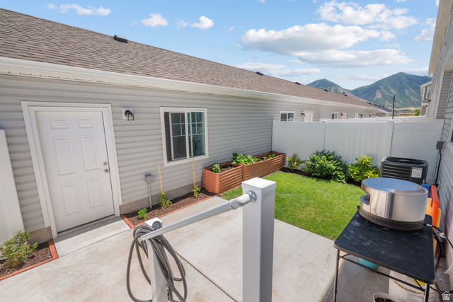 1693 North Center Point Lane Salem, UT 84653 - Photo 22 of 26 Concrete patio area with a privacy fence, a manicured lawn, and raised garden beds