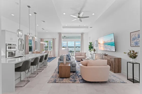 a living room with furniture kitchen view and a chandelier