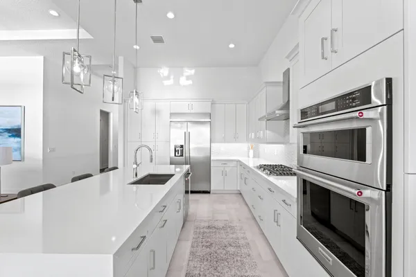 a large white kitchen with stainless steel appliances