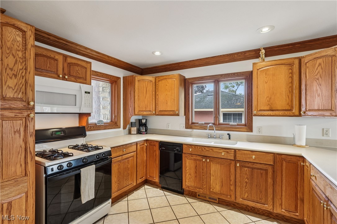 337 Cedar Point Road Sandusky, OH 44870 - Photo 11 of 50 Kitchen featuring gas range oven, brown cabinetry, white microwave, dishwasher, and light countertops