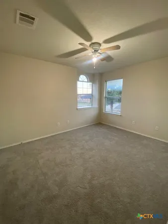 an empty room with windows and ceiling fan