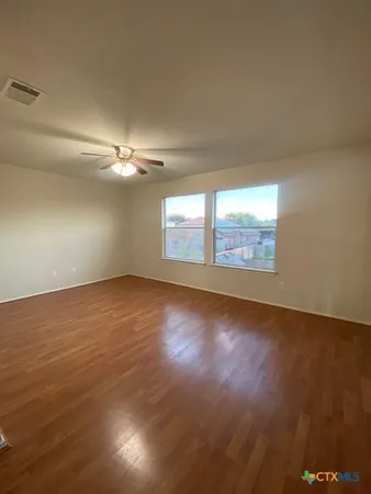 an empty room with wooden floor and windows