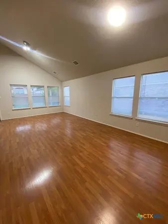 an empty room with wooden floor and windows