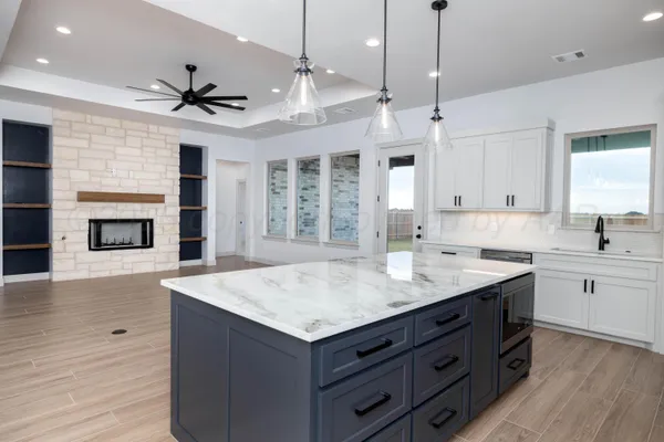 a kitchen with a stove center island a sink cabinets and wooden floor