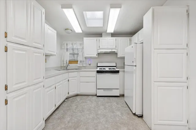 a kitchen with white cabinets and white appliances