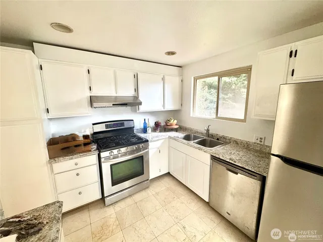 a kitchen with stainless steel appliances granite countertop a stove a sink and a refrigerator