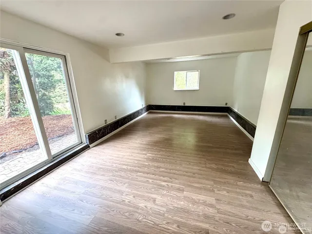 a view of empty room with wooden floor and fan