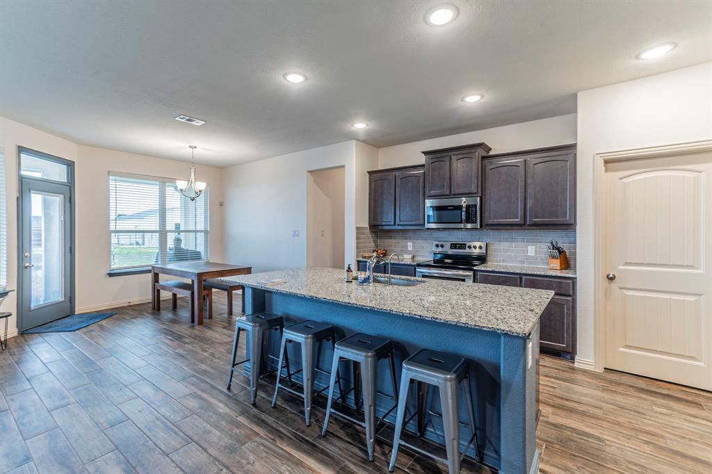 8432 Abner Road Terrell, TX 75161 - Photo 6 of 33 a kitchen with kitchen island granite countertop wooden floors and wooden cabinets