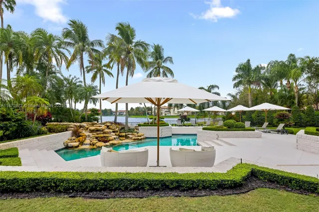 a view of a swimming pool with lawn chairs under an umbrella