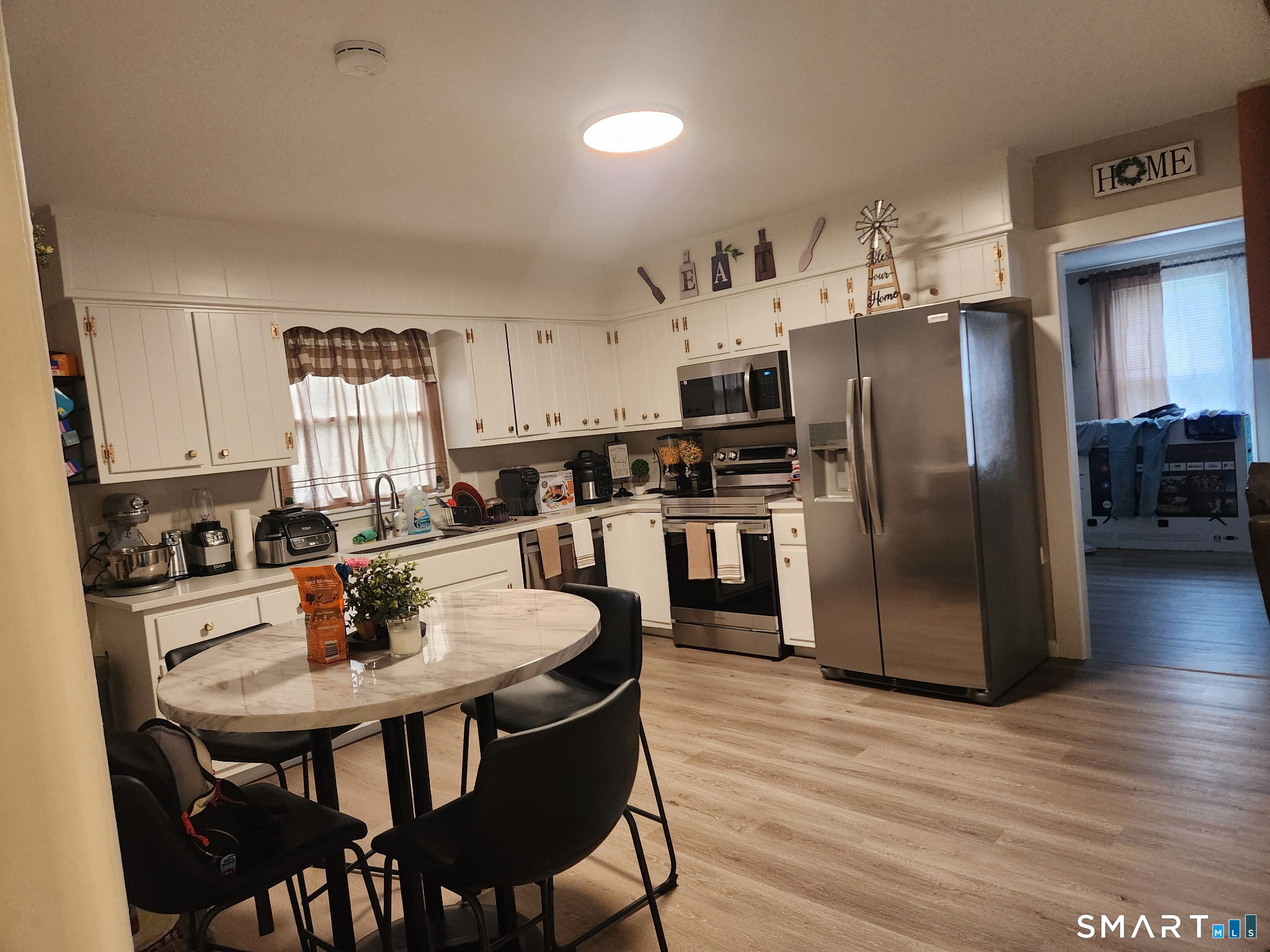 111-113 Sunset Avenue Meriden, CT 06450 - Photo 23 of 25 a kitchen with stainless steel appliances a dining table chairs refrigerator and microwave