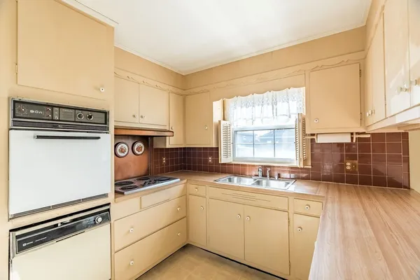 a kitchen with granite countertop a sink cabinets stainless steel appliances and a window