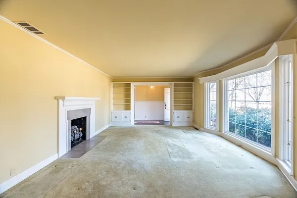 a view of an empty room with a fireplace and a window