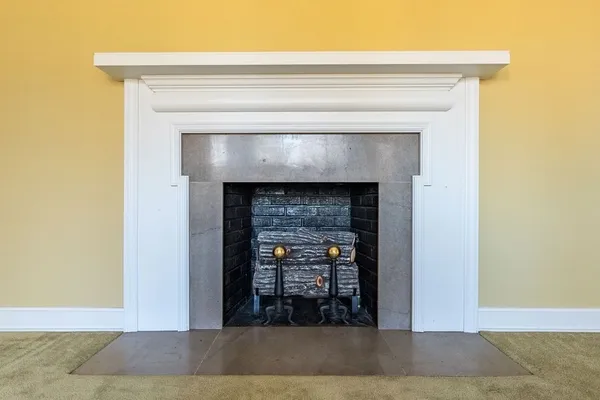 a view of an empty room with wooden floor and a fireplace