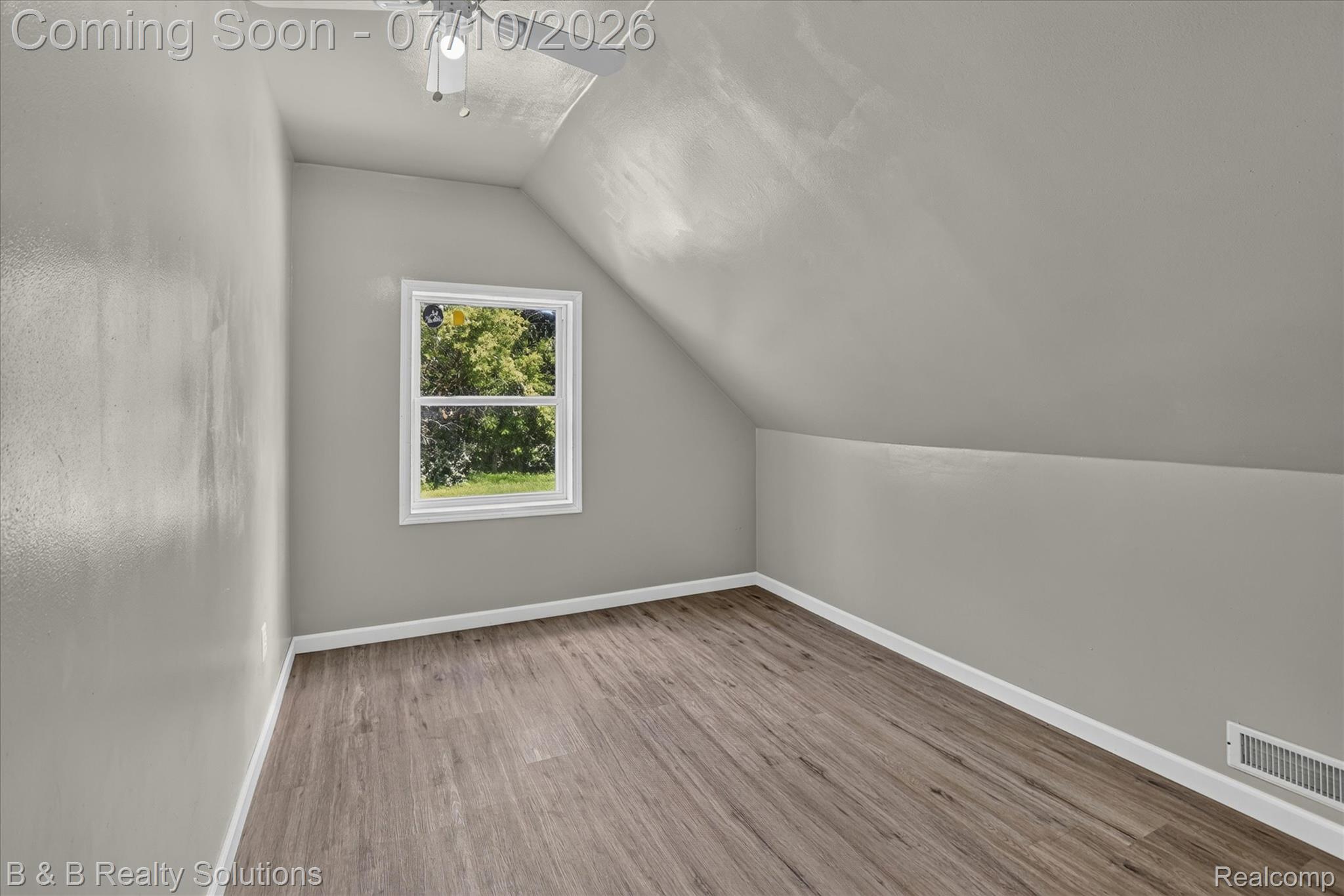 1564 East Burnside Road North Branch, MI 48461 - Photo 19 of 25 Attic room featuring wood-finish flooring, light gray walls, a white window frame with natural light, a ceiling fan with integrated lighting, and a white baseboard