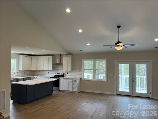 a open kitchen with white cabinets a fireplace and wooden floor