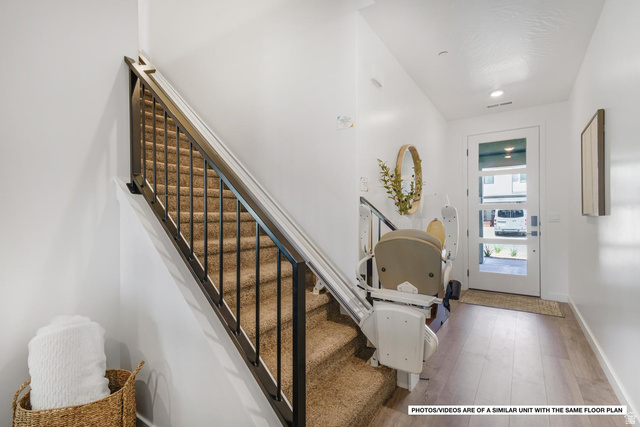 1702 Ripple Rock Drive, Unit 3171 Washington, UT 84780 - Photo 15 of 16 Entryway featuring a glass-paneled door, wood-finish flooring, and a carpeted staircase with a dark metal railing and an integrated stair lift