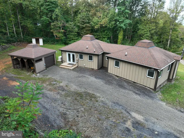 a view of a house with a yard plants and large tree
