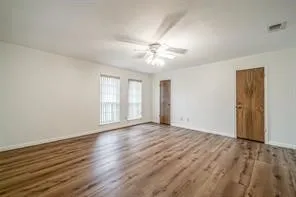 a view of an empty room with window and wooden floor