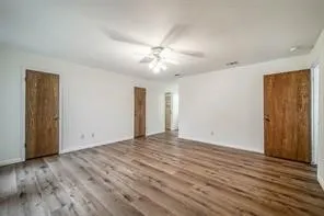 a view of empty room with wooden floor and fan