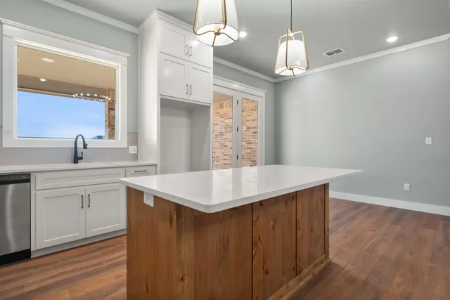 a kitchen with cabinets a sink dishwasher and a stove with wooden floor