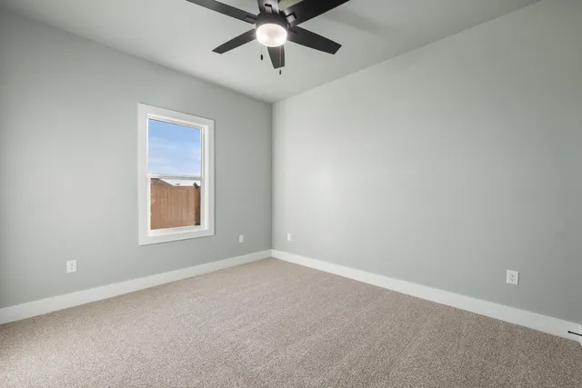 an empty room with a window and a fan