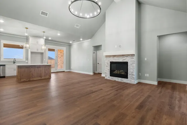 an empty room with wooden floor fireplace and windows