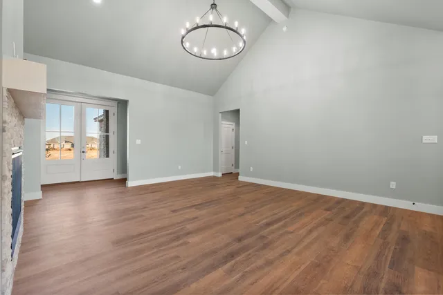 a view of an empty room with wooden floor and a large window