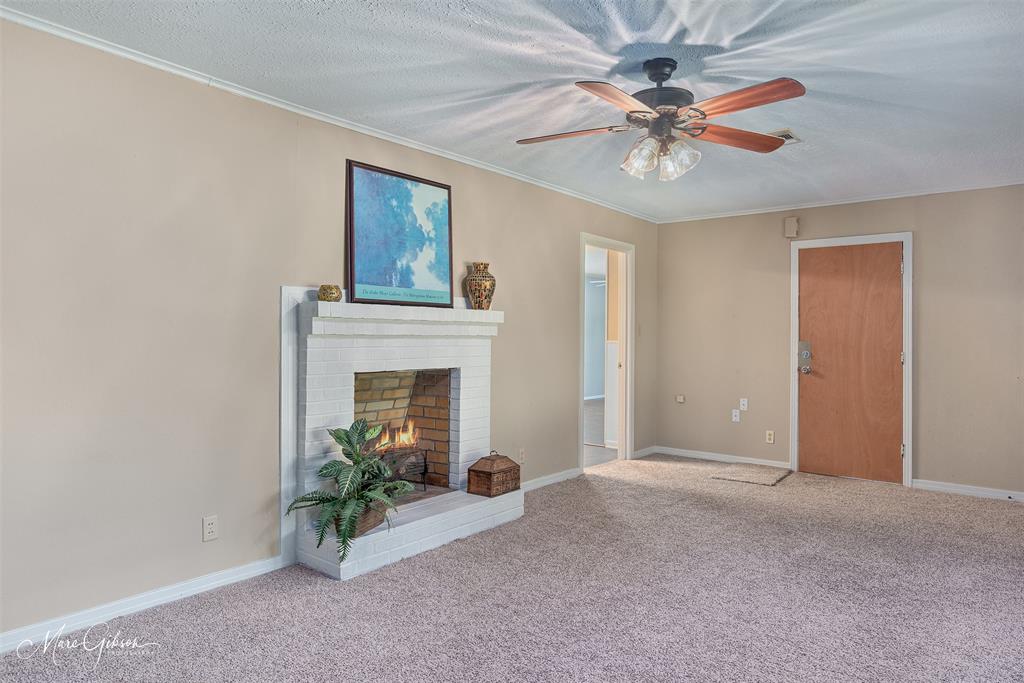 9342 Dean Road Shreveport, LA 71118 - Photo 5 of 18 Spacious room featuring a white brick fireplace with a hearth, light neutral-toned walls, and a ceiling fan with integrated lighting